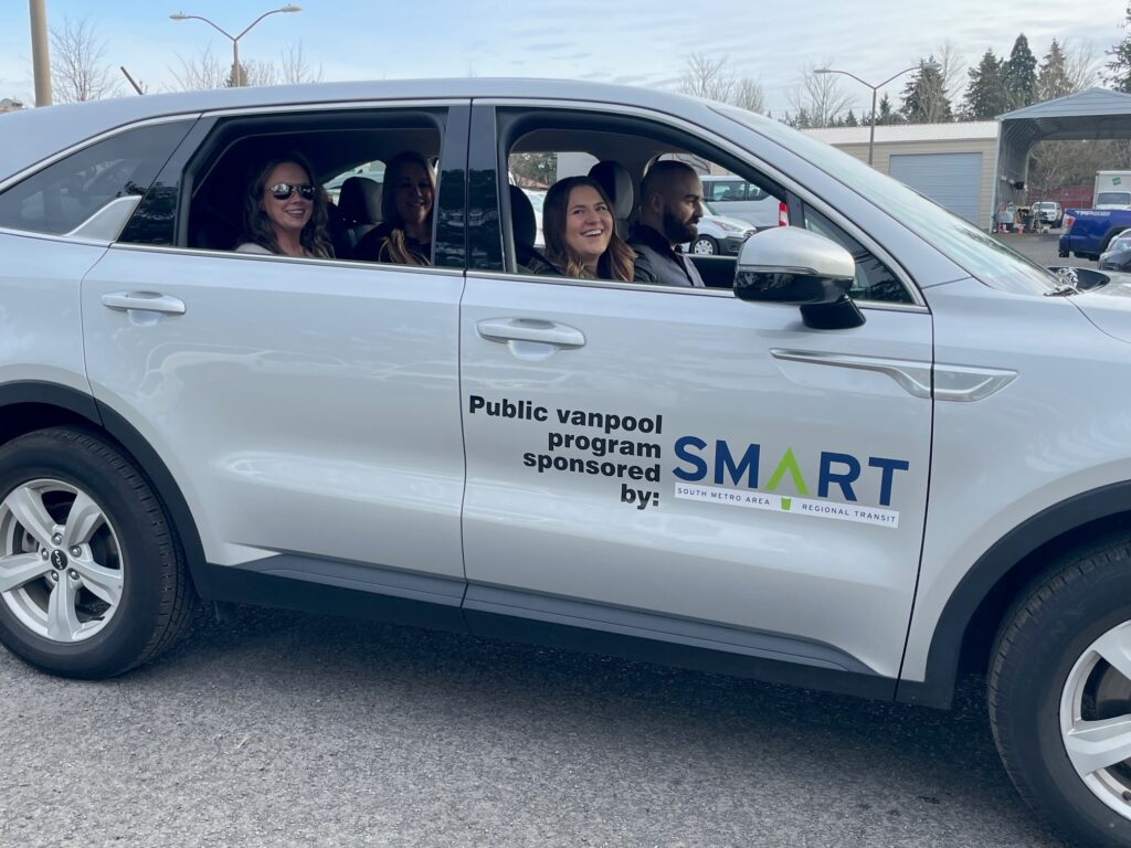 Driver and three smiling passengers inside a SMART Vanpool vehicle